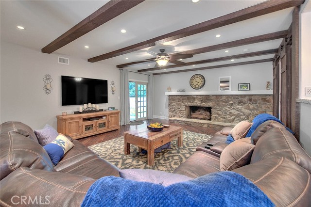 Beamed ceilings with recessed lighting and ceiling fan, dramatic rock fireplace