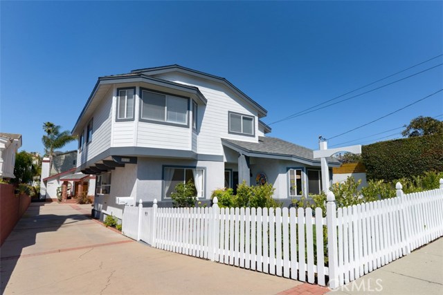 A shot of the driveway and white picket fence.  On the left side you can see the garden window in the kitchen.