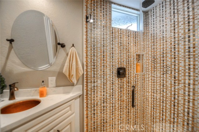 The downstairs bathroom has been remodeled to include a shower with spectacular tile and glass, a copper sink with quartz counter, and swivel mirror.