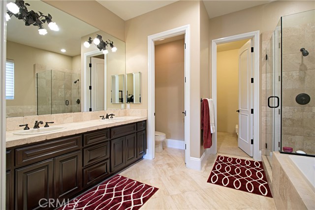 The master bath has double sinks, marble flooring, a glass shower & spa bathtub.