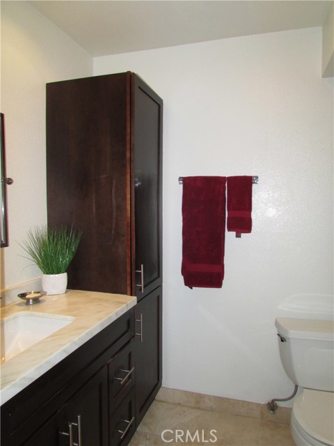 Second bath room with custom vanity and linen storage cabinet. Stone tile flooring.