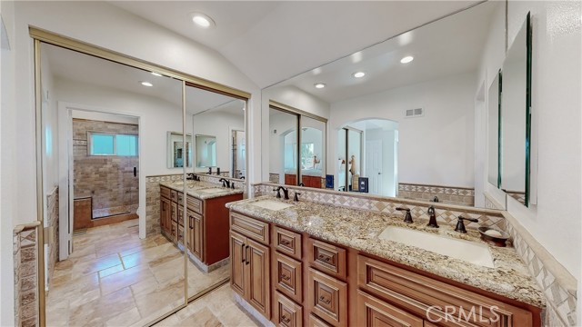 Dual sinks with one of a few mirrored closet doors.