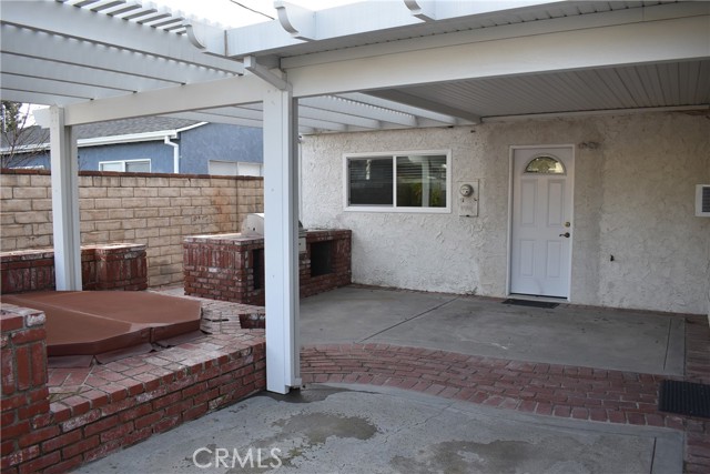 Back of house with spa and outdoor kitchen.