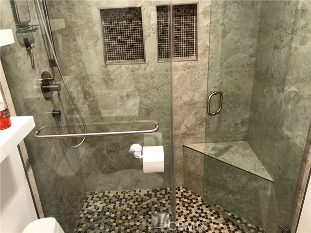 Fully tiled shower with thick glass doors and shower bench