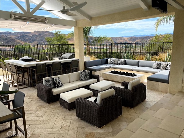 Covered patio with a double sided swim up bar, built in BBQ/bar area, overhead heaters and built in sofa around firepit