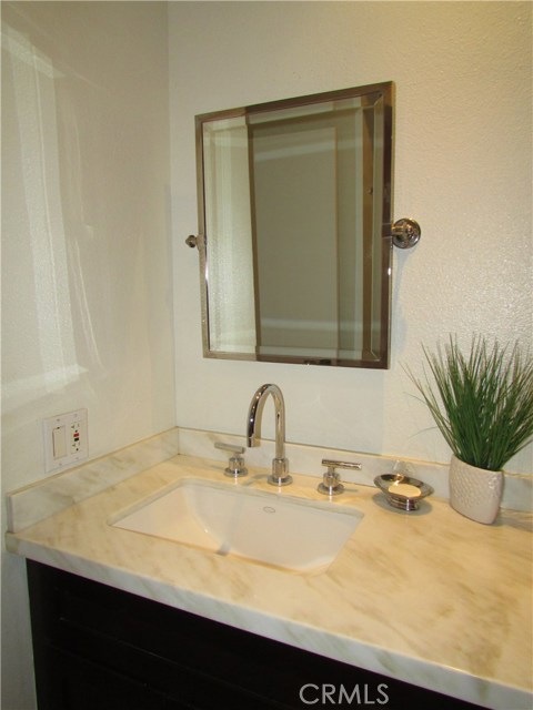 Second bedroom bath with custom vanity, marble counter, quality hardware, recess lighting and linen storage.