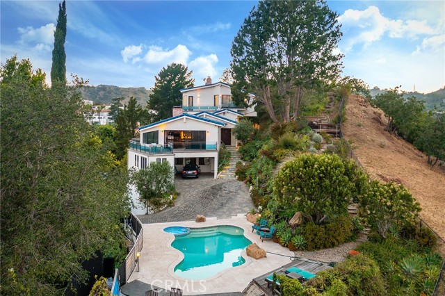 6909 Oporto Drive Los Angeles, California *PRICE IMPROVEMENT!* A TRUE COLLECTORS ITEM. ONE OF TWO PROPERTIES WITH DIRECT VIEWS TO THE HOLLYWOOD BOWL. With unparalleled 270° views of the Hollywood Bowl, the Hollywood sign, Griffith Observatory, Downtown Los Angeles, Sofi stadium, and the Sunset strip, 6909 Oporto is truly one of a kind. Celebrity owned, and upgraded with incredible care and attention to detail, this private, gated property has to be seen to be fully appreciated. Upon entry, the dazzling 400 gallon aquarium greets you on your way to the artfully designed living room, complete with a natural stone fireplace and sliding glass doors with city views. The kitchen boasts a large island with viking appliances, a pizza oven, and a breakfast nook. The curve-linear library bookshelves off the living room lead to the artistically designed main floor bathroom. The main level bedroom is currently converted into a media/ multipurpose room. Up a short flight of stairs you find the laundry room and second en suite bedroom/ games room. Up the second stairway you arrive at the primary bedroom, complete with private balcony and the best views on the property. The primary bathroom is a sight to behold. Designed by Holli Rogers, with custom tile masterfully manufactured in Israel, and built over the course of two years, the primary bath is reminiscent of Van Gogh's 'Starry Night'. Outside, the property connects seamlessly into the surrounding rock and trails that lead you to three separate viewing decks, all with different vantages of the Hollywood Bowl and surrounding areas. A large solar array is situated on the included neighboring lot. A pool and observation deck complete this Legacy property. This is truly a generational Hollywood collectors item.