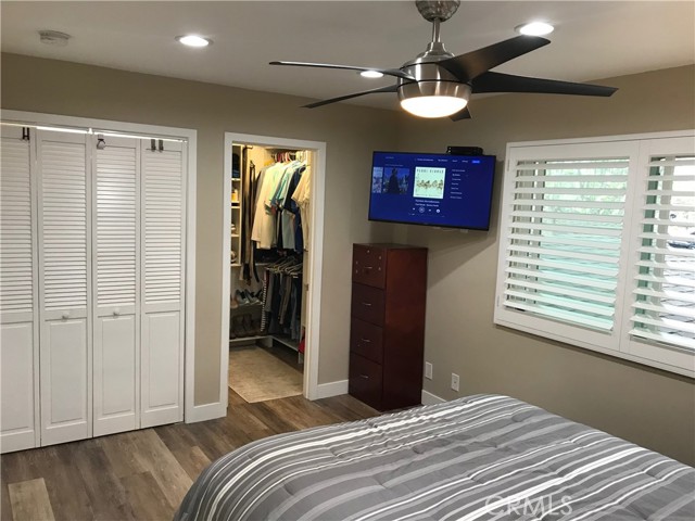 Primary bedroom with view of open walk-in closet entrance, laundry room and flatscreen TV