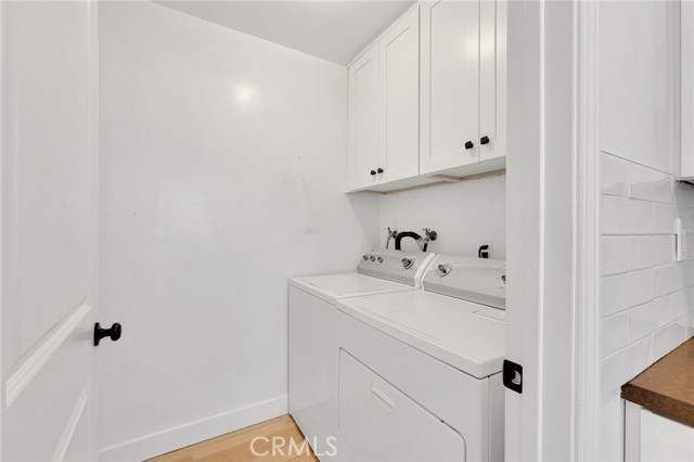 Convenient indoor laundry room with additional storage cabinets.