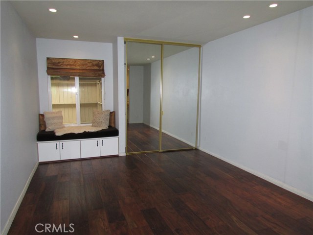 Master bedroom with hardwood floors, window seat/storage and two mirrored and lighted wardrobe closets. Note low voltage recess lighting.