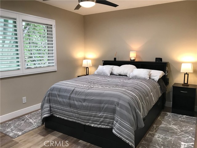 Primary bedroom with real wood plantation shutters and contemporary remote controlled ceiling fan