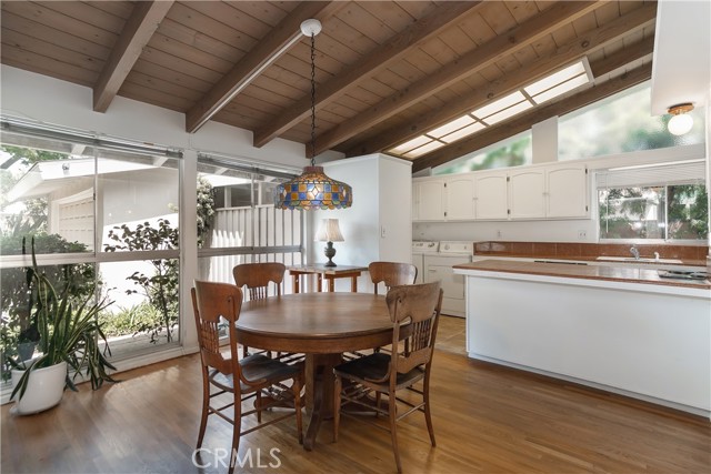 Breakfast room to kitchen with hardwood floors & open beam ceilings.