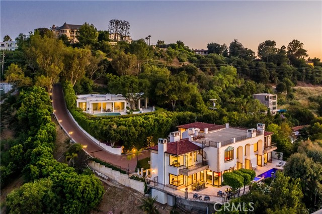 13319 Mulholland Drive Beverly Hills, California Perched on an ultra-private hillside on the coveted Mulholland Drive, this magnificent, gated, European-style villa captures panoramic views across the valley to the mountains. From the tree-lined motor court enter the foyer, where stately columns and archways lead to the ballroom-like great room, featuring 30’ ceilings, glass doors, clerestory windows, 8’ fireplace and Renaissance-style alfresco paintings. The chef’s kitchen showcases modern design, quartz countertops, custom cabinetry, Miele appliances and breakfast bar. Open, airy living areas segue to the wraparound, hillside terrace with heated pool and spa. Five bedrooms include the stunning master with a dressing room and fireplace. Home features include an expansive rooftop terrace with 360-degree views, marble and hardwood floors, lush gardens, stone fountains, library and 3-car garage. An entertainer’s retreat, the residence offers the utmost privacy and serenity in one California’s most iconic and desirable locations.