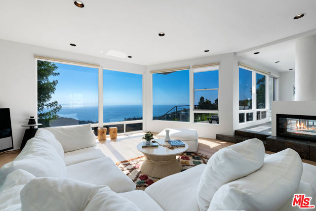 Spectacular modernist architecture highlights breathtaking views from nearly every room in this spacious and timeless estate designed by Vitus Matare'. With gorgeous slate and beech wood floors throughout, the home's enormous window walls command a panorama of mountains, ocean, and the distant lights of Palos Verdes. The step-down living room, with high ceilings, a built-in wet bar, and sweeping views, shares a double-sided fireplace with the dining room, which opens onto a full-width ocean-view deck with ample room for dining, lounging, and entertaining. Beyond the dining room, and also opening to the deck, is a beautiful family/dining/sitting room with slate floors and double-height ceilings. The kitchen, which has a skylight and a dining-room overlook, has gorgeous millwork, granite countertops, an island with bar seating, and top-of-the-line appliances as well as a walk-in pantry. On the upper level, along with four bedrooms, there is a large, open loft space that could be an office, yoga studio, game room, or media lounge. The bedrooms include a sensational owner's bedroom complete with high ceilings, huge window walls facing the views, beech wood floors, a sitting area, dual walk-in closets, a spacious ocean-view bath, and a lovely private balcony. Equipped with central air conditioning and solar, the residence has a two-car garage plus a large, ocean-view lawn for entertaining, recreation, and, potentially, a pool. Lush palms and other tropical plantings give this well-designed Eastern Malibu architectural estate the atmosphere of a vacation getaway.