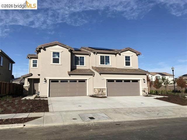 Two-story stucco exterior with stone accents, twin attached garages, concrete driveways, and a tile roof