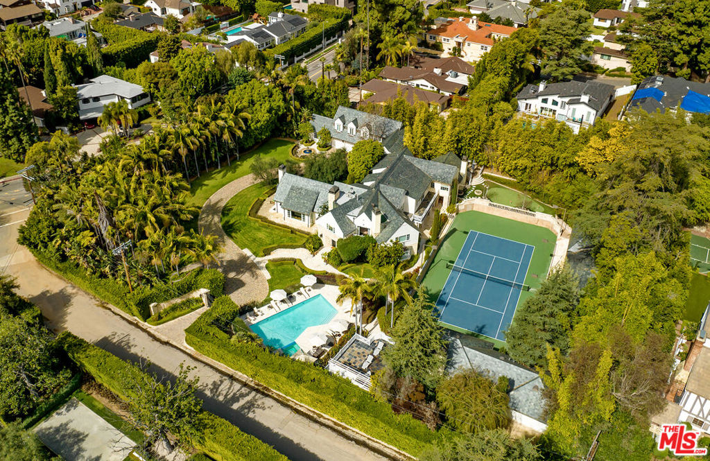 Nestled behind private gates and accessed via a charming stone-paved driveway, this tennis court estate embodies the perfect blend of timeless elegance and a prestigious lineage marked by Hollywood glamour. Originally crafted in 1941 by the renowned Paul Williams with an extensive expansion and full scale meticulous remodel from 2007-2014 by the current owner with no expense spared.  Spectacular grounds, full 2 lane vintage bowling center building (perfect also for one of the largest gyms, office spaces or recording studios) complete this iconic and timeless estate.The main residence boasts 7 beds and 7 baths curated by the legendary Ralph Lauren. Luxurious master suite with his and her baths and walk-in wardrobe closets with a private massage room/extra office, oversized guest suite with private living room, 3 family bedrooms with separate hallway, 2 service suites and two-story guest house with private guest garage and entry. Spectacular living room all opening to the outside, large office located and tucked off the main entry, lower-level theater with bathroom perfect for late night entertaining with elegant bar service area.  Elegant, oversized dining room, family kitchen, breakfast room and stunning outdoor dining area overlooking the lit tennis court. Strategically located just minutes away from the Beverly Hills Hotel, circled in spectacular mature landscaping and towering tree-lined perimeter this estate is one of the last and finest multiple structure estates to be built, in the best location accessible to studios and Beverly Hills shops and restaurants.