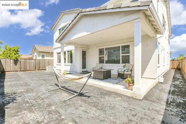 Rear view of property featuring a fenced backyard, stucco siding, and a patio area