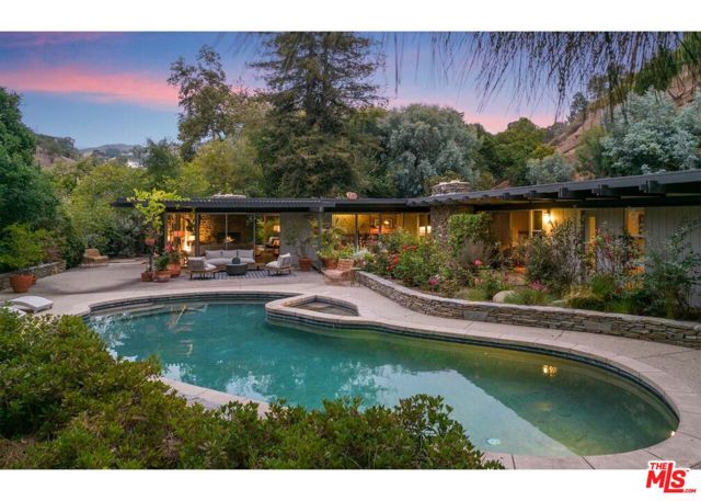 1030 Rivas Canyon Road Pacific Palisades, California Never before on the market. This extraordinary example of mid-century modern architecture awaits the discerning buyer. The property comprises ~1.4A up a secluded driveway on a private road in prime Pacific Palisades. From 1958-1960, renowned architects Karl Klokke and Paul Wuesthoff designed and built this home as an avant-garde residence for a prominent local family. Sited on the lot to capture the beauty of the gardens and majestic trees, every room opens to a beautiful green private oasis. Floor to ceiling windows, sliding glass doors, post and beam design, flat roof and large overhangs define this one story masterpiece of indoor outdoor California living. Serenely private, the outside sitting and dining areas surround the magical pool, spa and rose garden. From the front door, a long gallery hall leads to a sunken living room with a cement floor, stone fireplace and walls of glass, continuing to the simple yet elegant dining room, with built-in cabinets and a modernist bar. The open plan kitchen seamlessly shares space with the family room with half walls and brick fireplace. Two separate bedroom wings allow simple functionality; three bedrooms on one side of the house and the primary suite on the other. The primary suite has a large bedroom, separate office, a zen meditation and massage room, two baths and a small kitchen. A bonus exterior studio/workout room is adjacent to the carport, the fruit orchard and orchid house. Original plans available. Trust sale. See Agent Remarks. First time offers will be reviewed is on August 2nd. No open houses, all showings by appointment only.