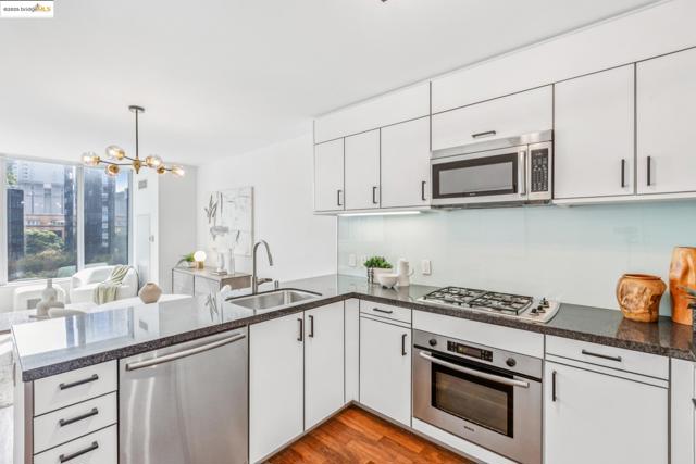 Kitchen with a peninsula, appliances with stainless steel finishes, a chandelier, dark wood-type flooring, and white cabinets