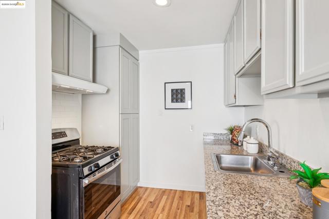Kitchen featuring stainless steel gas range, light wood-type flooring, under cabinet range hood, tasteful backsplash, and recessed lighting
