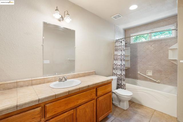 Full bath featuring shower / bath combination with curtain, vanity, light tile patterned flooring, a textured wall, and recessed lighting