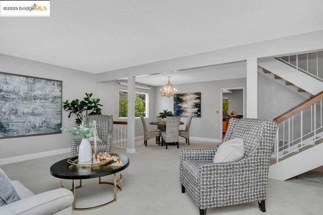 Carpeted living room featuring stairs, a chandelier, and a textured ceiling
