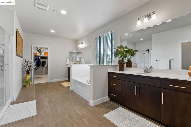 Bathroom featuring vanity, a bath, a shower stall, recessed lighting, and a walk in closet