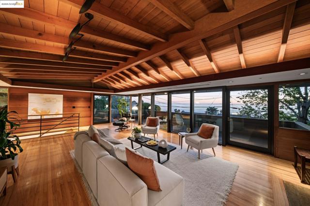 Living area with wooden ceiling, light wood finished floors, wooden walls, and floor to ceiling windows
