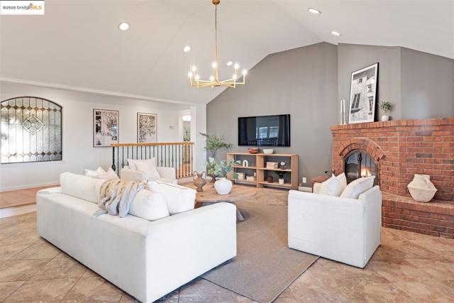 Living area with recessed lighting, a chandelier, a brick fireplace, and vaulted ceiling