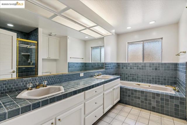 Full bathroom with double vanity, a garden tub, a shower stall, tile patterned floors, and recessed lighting