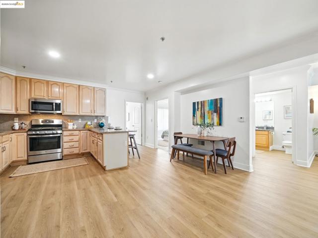 Kitchen with light brown cabinets, stainless steel appliances, a peninsula, crown molding, and light wood-style floors