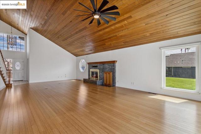 Unfurnished living room with wooden ceiling, high vaulted ceiling, stairway, light wood-style flooring, and a ceiling fan