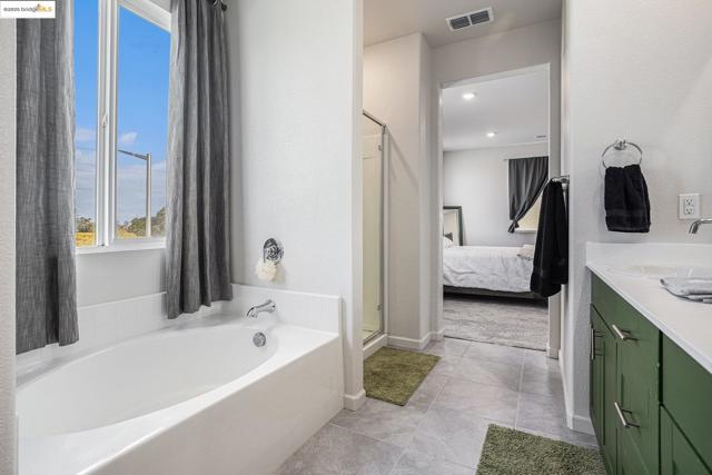 Ensuite bathroom with a bath, a stall shower, vanity, and light tile patterned floors