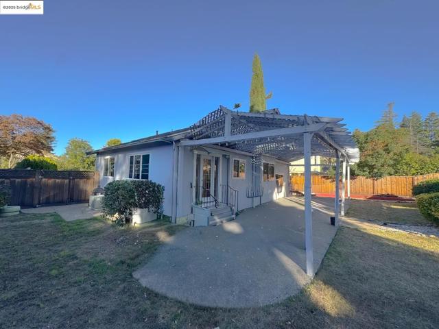 Rear view of property with a patio area, a fenced backyard, and a pergola