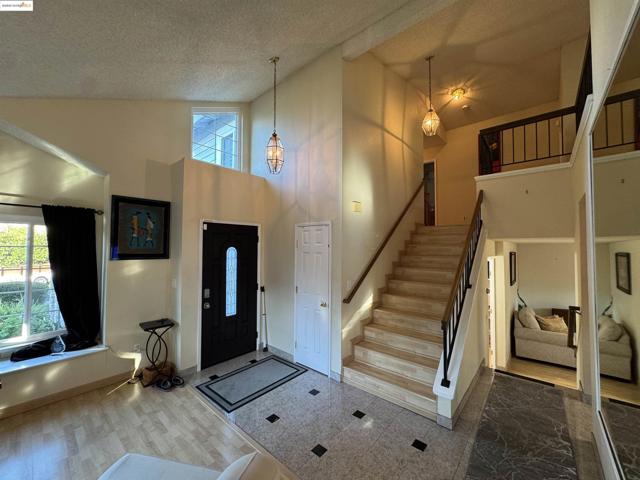 Foyer with high vaulted ceiling, stairway, a textured ceiling, and wood finished floors