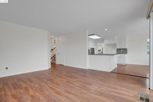 Unfurnished living room with light wood-type flooring, stairway, and recessed lighting