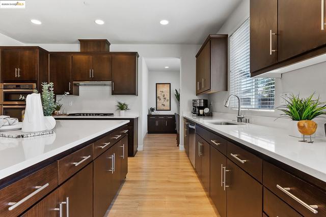 Kitchen featuring light wood-type flooring, light countertops, recessed lighting, dark brown cabinets, and appliances with stainless steel finishes