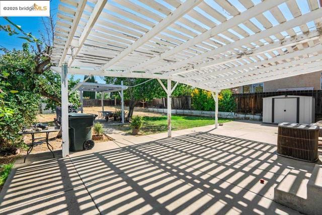 Fenced backyard featuring a storage unit, a patio area, and a pergola