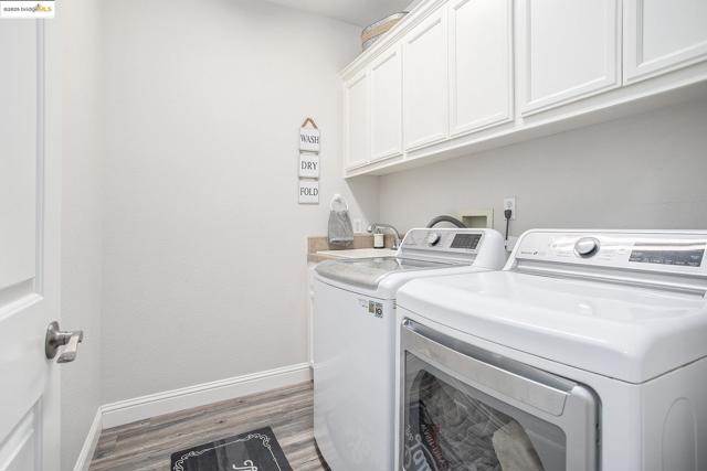 Washroom with utility sink, laminate wood finished floors, upper cabinet space, and gas or electric dryer hook-ups.