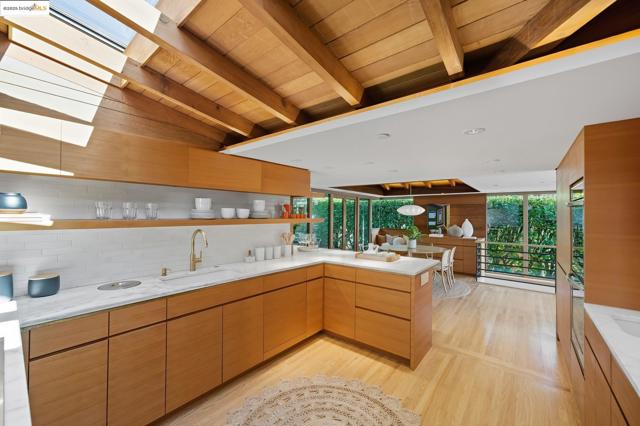 Kitchen with modern cabinets, plenty of natural light, light wood-style flooring, open shelves, and a wooden ceiling with exposed beams