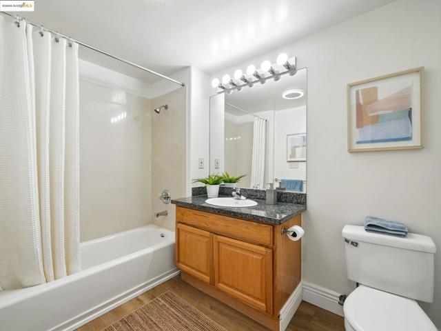 Bathroom with shower / bath combo with shower curtain, wood finished floors, and vanity