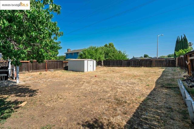 Fenced backyard featuring a storage unit