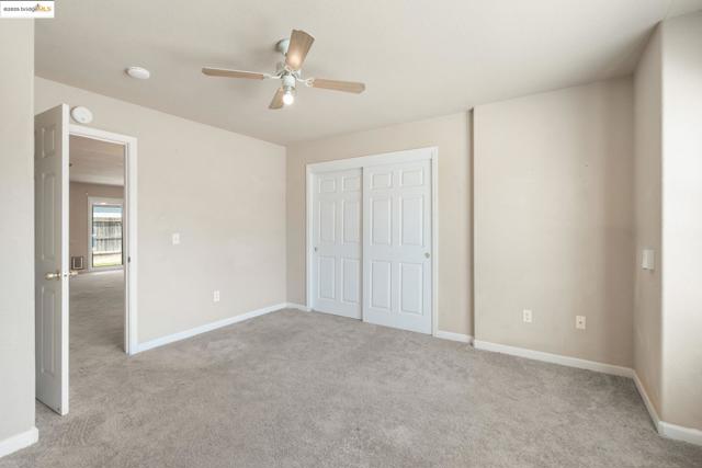 Unfurnished bedroom with light carpet, ceiling fan, and a closet