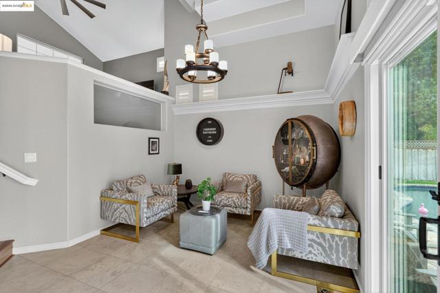 Living area with a chandelier, stairway, high vaulted ceiling, and tile patterned flooring