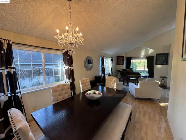 Dining area featuring vaulted ceiling, wood finished floors, a textured ceiling, and a chandelier