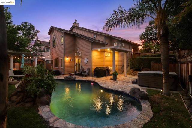 Back of property with a hot tub, a patio area, and a chimney