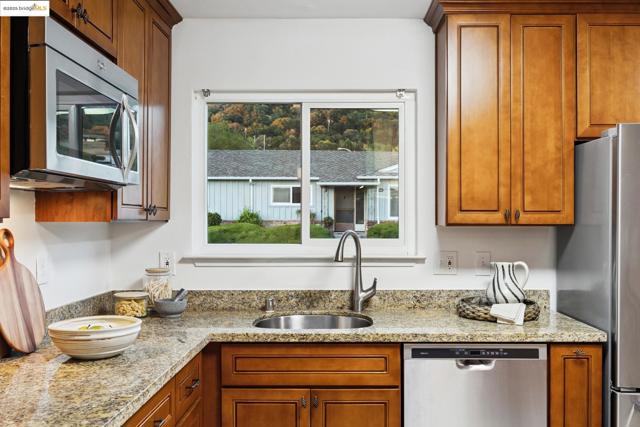 Kitchen featuring light stone countertops, brown cabinets, and appliances with stainless steel finishes