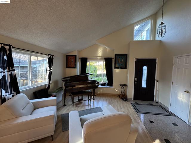 Foyer entrance with a textured ceiling, light wood-type flooring, and high vaulted ceiling