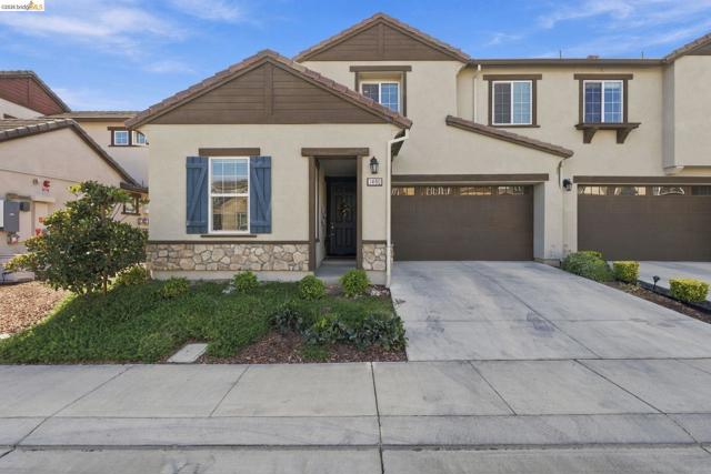 Stucco exterior with stone accent, decorative blue shutters, attached two-car garage, and concrete driveway
