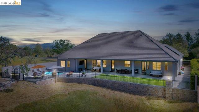 Digitally Altered. Back of property at dusk with a patio area, a fenced backyard, and outdoor furniture